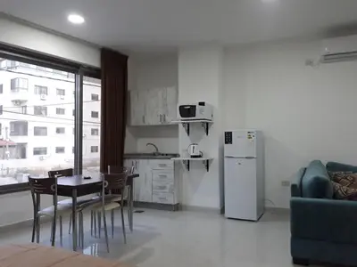 a kitchen with a table and chairs and a refrigerator at Furnished Apartments Near McDonald's Al-Madina Al-Monawara St in Amman