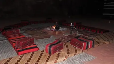 a group of red chairs with a table and a candle at Salem Camp in Wadi Rum