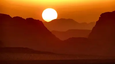 a sunset in the desert with the sun in the sky at Salem Camp in Wadi Rum
