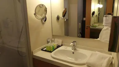 a bathroom with a sink and a mirror at Amman Airport Hotel in Al Qasţal