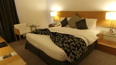 a hotel room with a large bed and a chair at Amman Airport Hotel in Al Qasţal