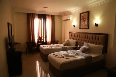 a hotel room with two beds and a couch at Grape Village Hotel in Amman