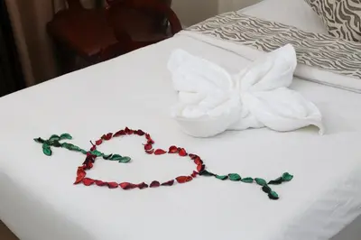 a heart necklace on a bed with a flower at Grape Village Hotel in Amman