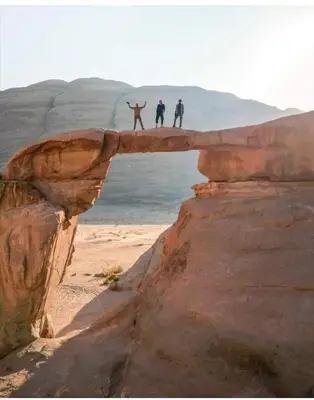 three people standing on a bridge over the beach at Bedouin Village Hostel in Wadi Rum