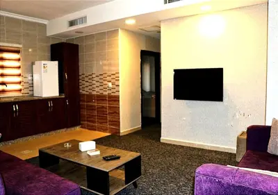 a living room with a couch and a tv on a wall at Skylight apartments in Amman