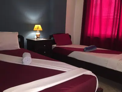 a room with two beds with red curtains and a lamp at Nobel Hotel in Amman