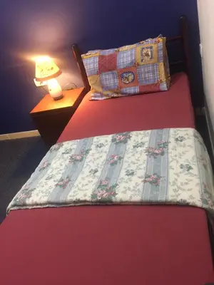 a bedroom with a bed with a quilt and a lamp at Nobel Hotel in Amman