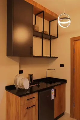 a kitchen with a sink and a black refrigerator at Al Jawhara Hotel Suites in Amman