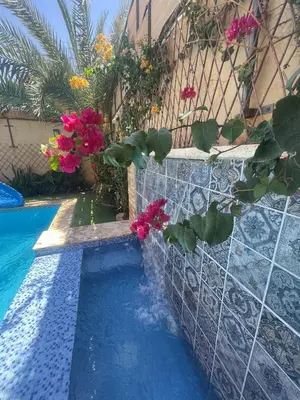 a swimming pool with pink flowers and a fence at Orient Villa-Dead Sea in Sowayma