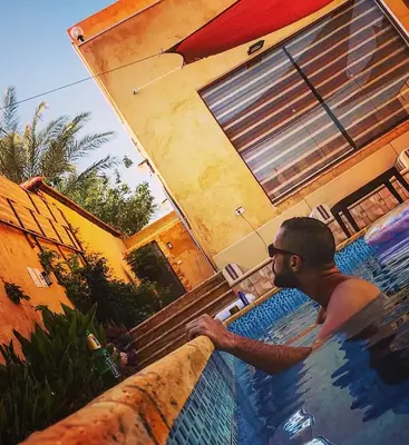 a man in a swimming pool next to a house at Orient Villa-Dead Sea in Sowayma