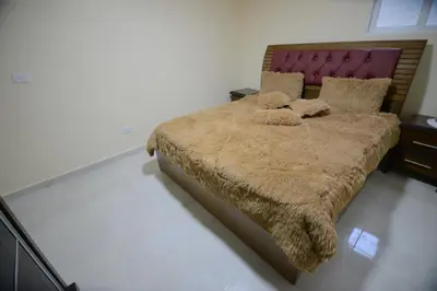 a bedroom with a large bed with a red headboard at Juniper House in Wadi Musa