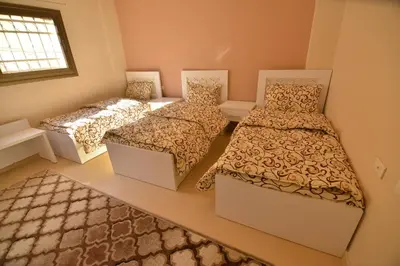 a room with three beds and a window at Juniper House in Wadi Musa