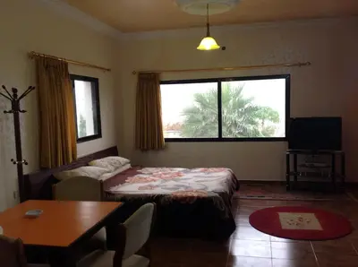 a living room with a bed and a table and a window at Murshed Motel in Ash Shūnah ash Shamālīyah