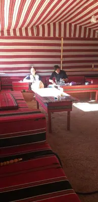 a group of people sitting in a tent with tables at Bronze Mountains Camp Wadi Rum in Aqaba