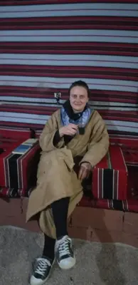 a man in a coat sitting on a couch at Bronze Mountains Camp Wadi Rum in Aqaba