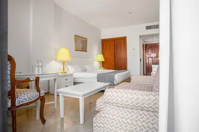 a hotel room with two beds and a desk and a couch at Grand Hotel Madaba in Madaba