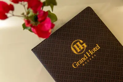 a black card with a gold logo on it next to flowers at Grand Hotel Madaba in Madaba