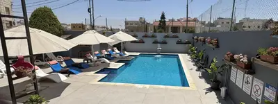 a swimming pool with chairs and umbrellas on a building at Grand Hotel Madaba in Madaba