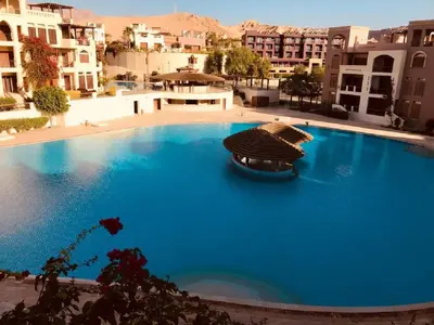 a large blue swimming pool in a city with buildings at Sea View Apartment at Tala Bay Resort in Aqaba in Aqaba