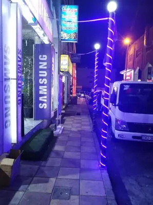 a street with neon signs and a van parked on the street at Aqaba Roza in Aqaba