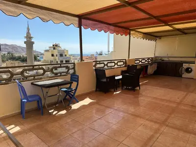 a balcony with a table and chairs and a view at Relax House For Studio Rooms Apartments ريلاكس هاوس للشقق المفروشة in Aqaba