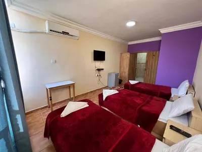 a hotel room with three beds and a tv at Dweik Hotel 1 in Aqaba