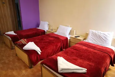 a room with three beds with red sheets and white towels at Dweik Hotel 1 in Aqaba