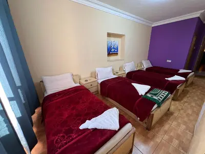 a room with three beds with red sheets at Dweik Hotel 1 in Aqaba