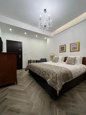 a bedroom with a large bed and a chandelier at Bonita Inn in Amman