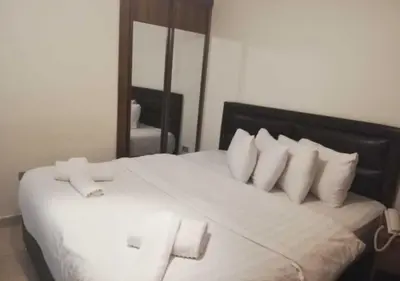 a large white bed with white pillows in a bedroom at Shami Plaza Hotel in Amman