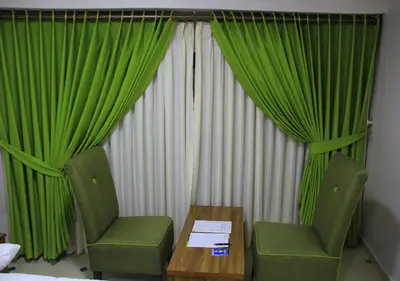 a room with green curtains and a table and chairs at Shami Plaza Hotel in Amman