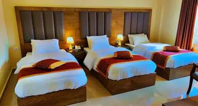 a hotel room with two beds and two lamps at Shaqilath Hotel in Wadi Musa