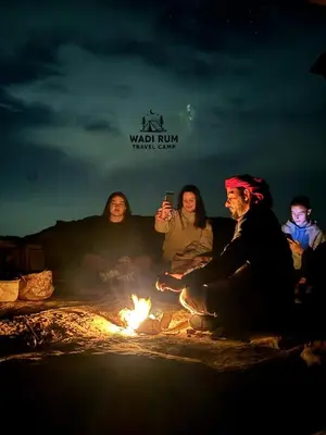 a group of people sitting around a fire at Wadi Rum Travel camp in Wadi Rum