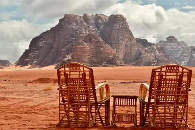 two chairs in the desert with mountains in the background at Wadi Rum Travel camp in Wadi Rum