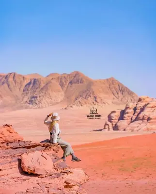 a man standing on a rock in the desert at Wadi Rum Travel camp in Wadi Rum