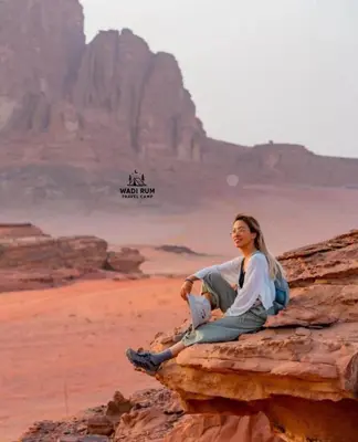 a woman sitting on a rock in the desert at Wadi Rum Travel camp in Wadi Rum