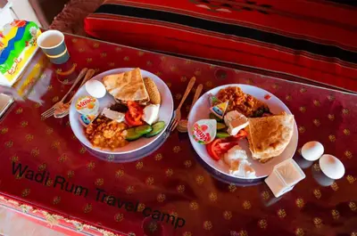 a table with two plates of food on a table at Wadi Rum Travel camp in Wadi Rum