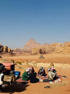 a group of people sitting in the desert at Wadi Rum Travel camp in Wadi Rum
