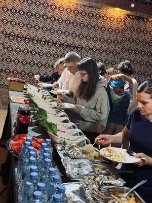 a group of people standing around a buffet with plates of food at Wadi Rum Travel camp in Wadi Rum