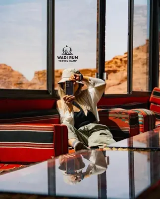 a woman sitting on a bus taking a picture on her cell phone at Wadi Rum Travel camp in Wadi Rum