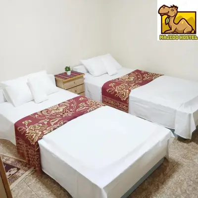 a room with three beds and a horse logo on the wall at Majido Hotel in Wadi Musa