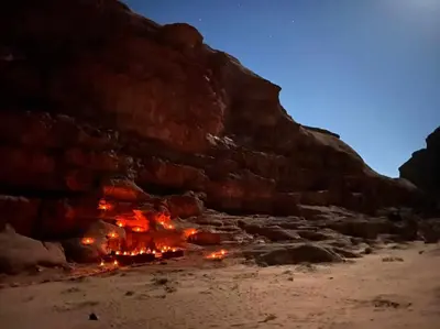 a bonfire on the beach near a cliff at Bedouin host camp& with tour in Wadi Rum