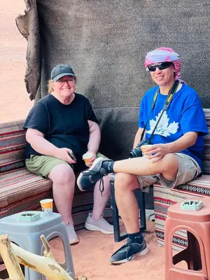 two people sitting on a bench with drinks at Rum Paradise luxury camp& BUBBLE in Wadi Rum