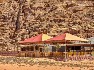 a restaurant with red and yellow umbrellas in front of a mountain at Rum Paradise luxury camp& BUBBLE in Wadi Rum