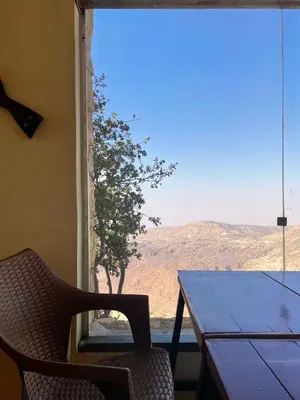 a table and a chair in a room with a window at Jabal Dana Hotel - the highest hotel in Jordan in Dana
