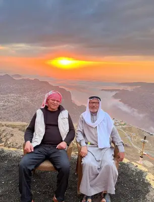 two people sitting on a chair on top of a mountain at Jabal Dana Hotel - the highest hotel in Jordan in Dana