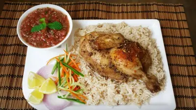 a plate of food with chicken and rice and a bowl of sauce at Arabesque Hotel in Amman