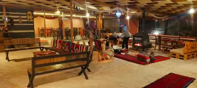 a living room with a fireplace and people in a room at Petra Wassaif Camp in Wadi Musa
