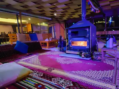 a living room with a fireplace in the middle of a room at Petra Wassaif Camp in Wadi Musa