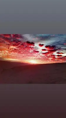 a sunset on a beach with the sun setting at Mujib Castle Gate Camp in Dhībān
